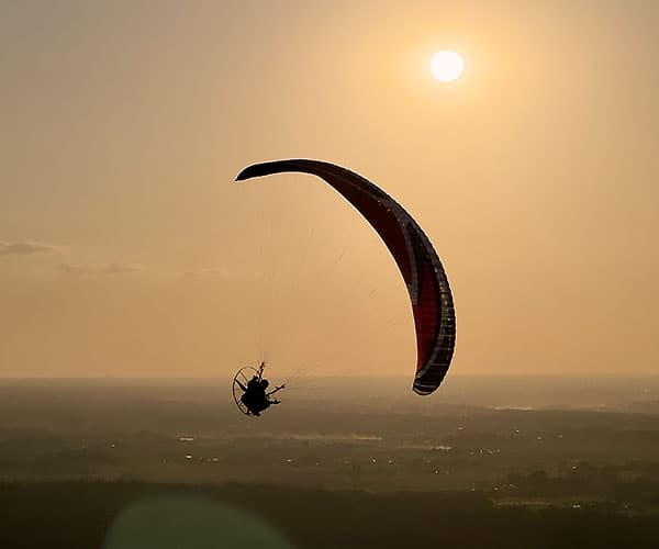 Paramotor pilot flying over scenic landscape